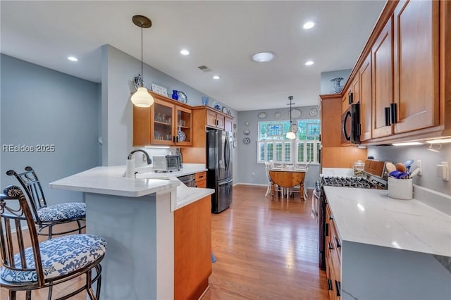 kitchen featuring black appliances, sink, a kitchen bar, hanging light fixtures, and kitchen peninsula