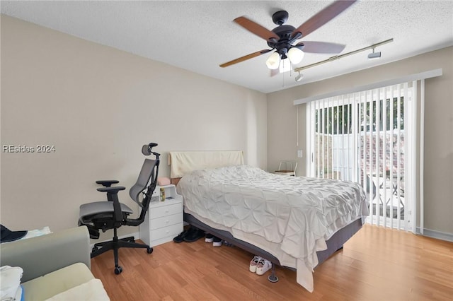 bedroom with ceiling fan, wood-type flooring, and a textured ceiling