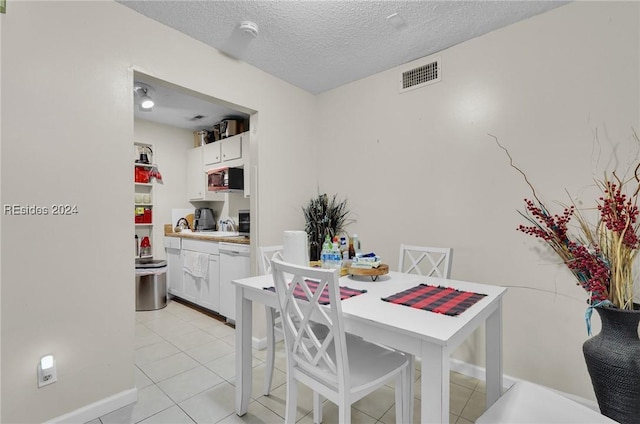 dining space featuring light tile patterned flooring and a textured ceiling