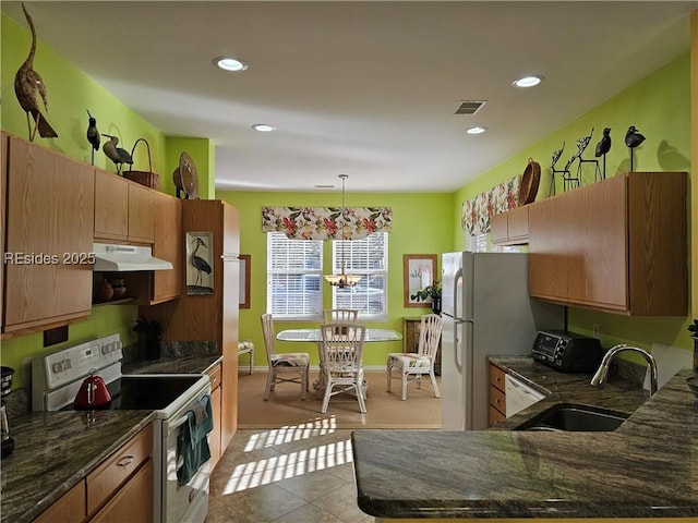 kitchen with hanging light fixtures, light tile patterned flooring, sink, and white appliances