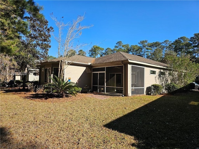 rear view of house with a lawn and a sunroom