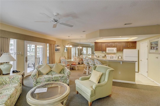 living room with a textured ceiling, light colored carpet, and ceiling fan