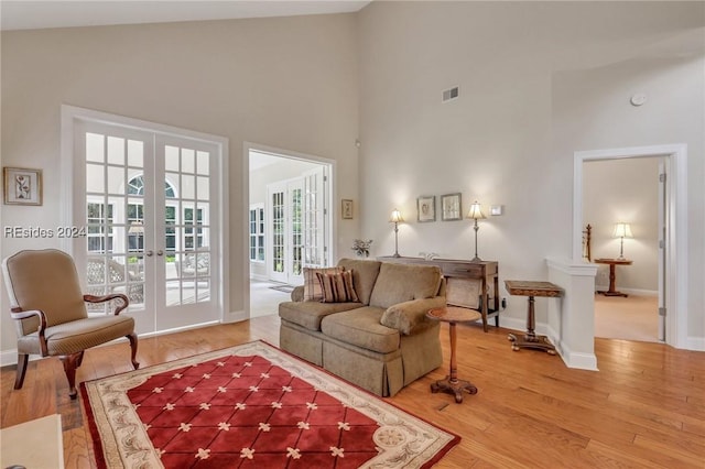 living room with hardwood / wood-style flooring, high vaulted ceiling, and french doors