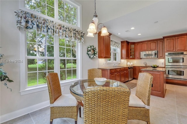 kitchen featuring pendant lighting, tasteful backsplash, sink, stainless steel appliances, and an inviting chandelier