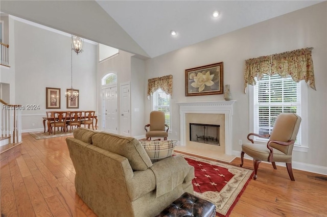 living room with high vaulted ceiling, an inviting chandelier, and light hardwood / wood-style flooring