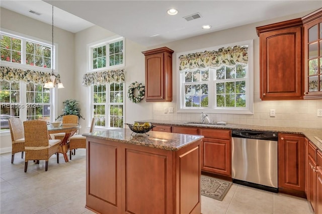 kitchen with sink, light tile patterned floors, dishwasher, hanging light fixtures, and light stone countertops