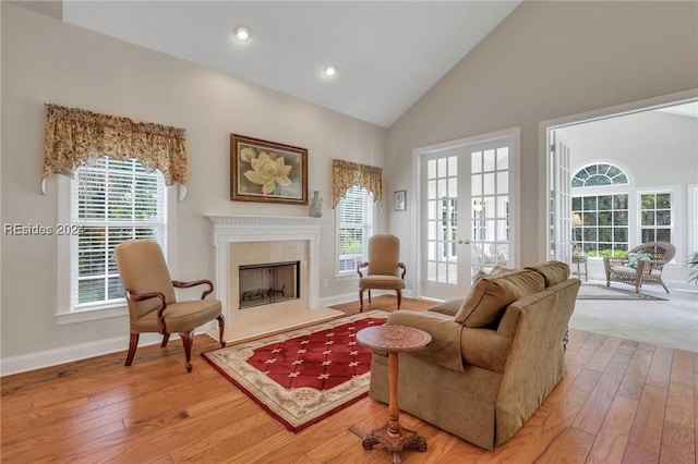 living area featuring hardwood / wood-style flooring, a high end fireplace, french doors, and plenty of natural light