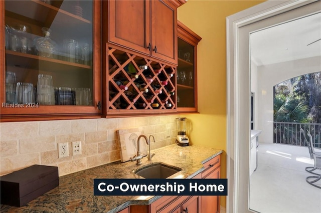 bar featuring stone countertops, sink, and backsplash