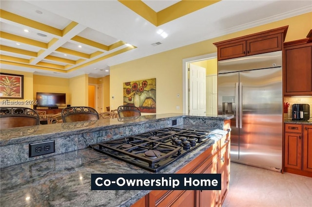 kitchen with dark stone counters, coffered ceiling, stainless steel built in fridge, and black gas cooktop