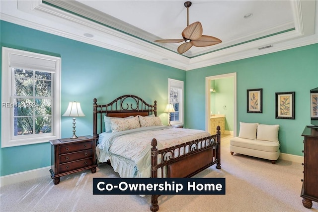 carpeted bedroom featuring crown molding, a tray ceiling, ceiling fan, and ensuite bathroom