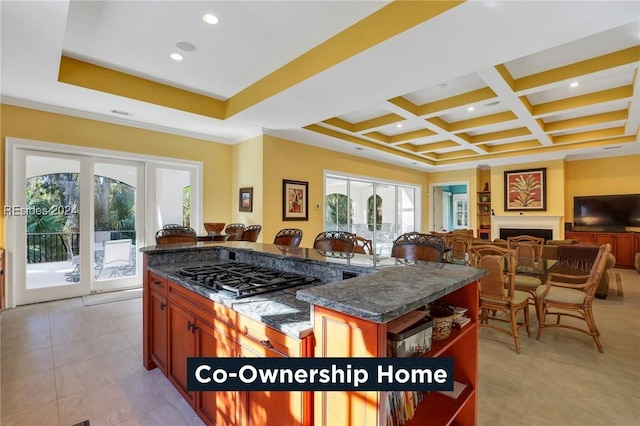 kitchen with stainless steel gas stovetop, dark stone counters, a center island, coffered ceiling, and beam ceiling