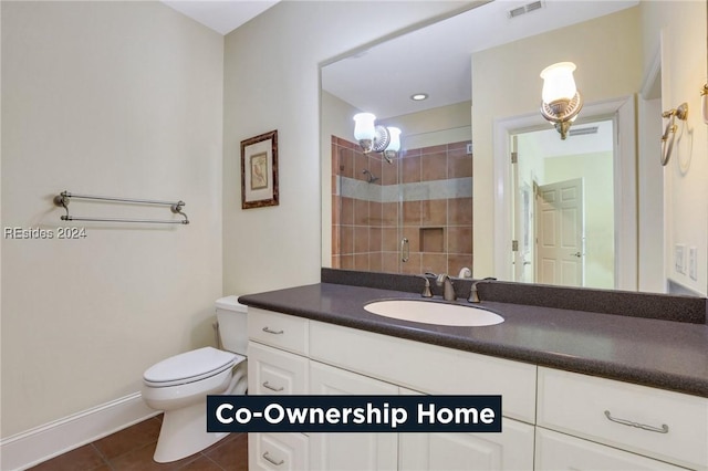 bathroom featuring tile patterned flooring, vanity, an enclosed shower, and toilet