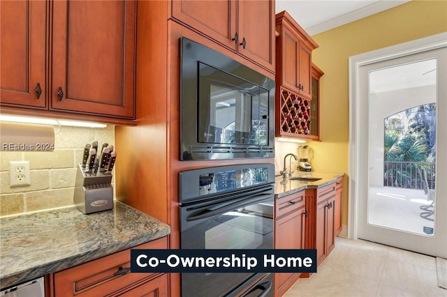 kitchen featuring stone countertops, sink, decorative backsplash, light tile patterned floors, and black appliances