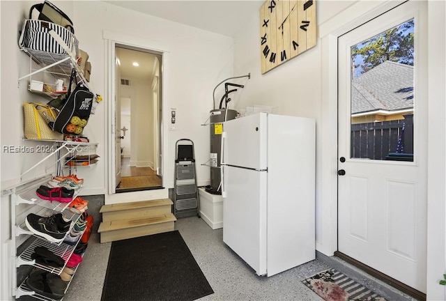 interior space with electric water heater and white fridge