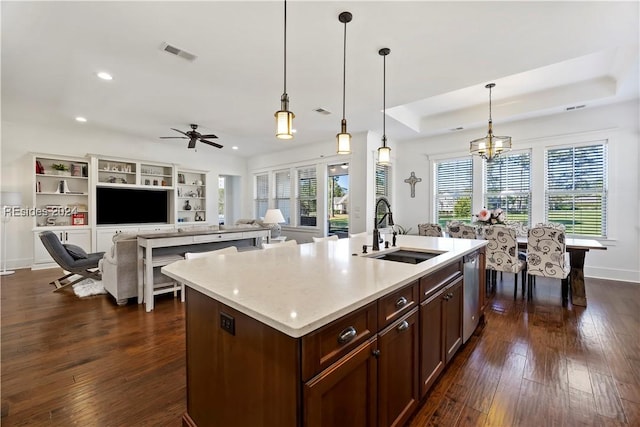 kitchen featuring pendant lighting, sink, dark hardwood / wood-style flooring, a kitchen island with sink, and a tray ceiling