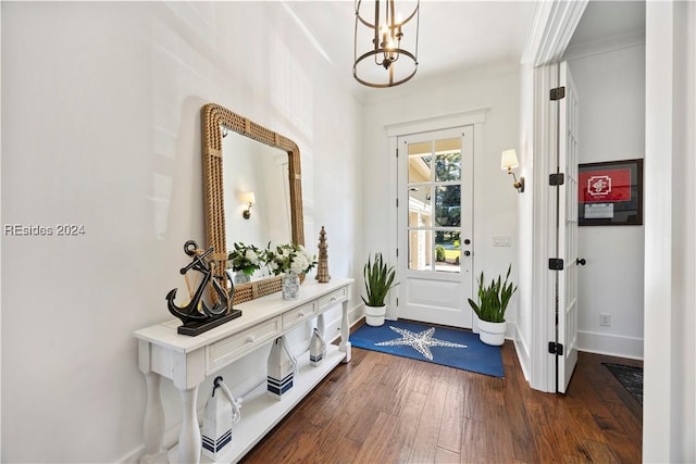 doorway to outside with ornamental molding, dark wood-type flooring, and an inviting chandelier