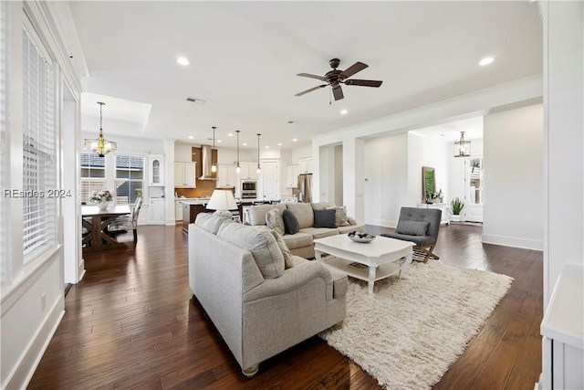 living room with dark hardwood / wood-style flooring and ceiling fan with notable chandelier