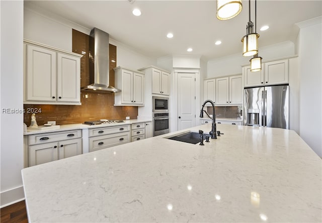 kitchen with sink, wall chimney range hood, stainless steel appliances, tasteful backsplash, and decorative light fixtures