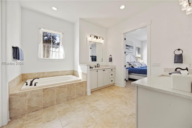 bathroom featuring tiled tub and vanity