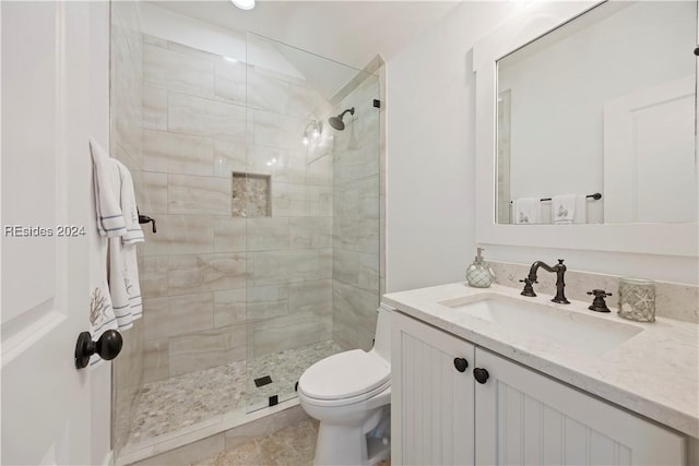 bathroom featuring tiled shower, vanity, and toilet