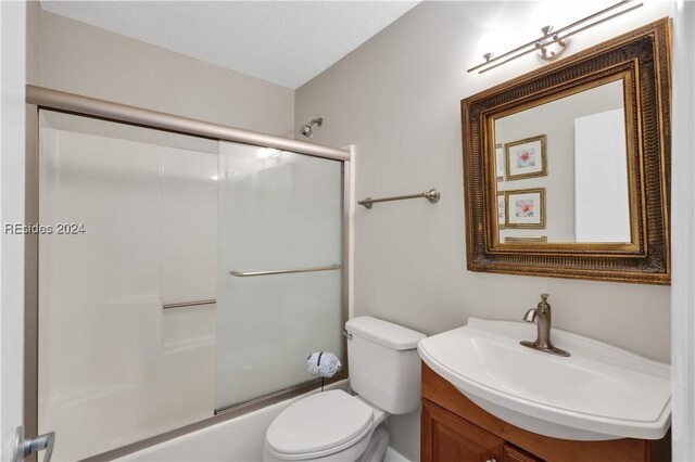 full bathroom with enclosed tub / shower combo, vanity, and toilet