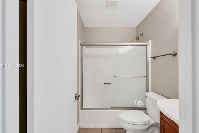 full bathroom with bath / shower combo with glass door, tile patterned floors, toilet, and vanity