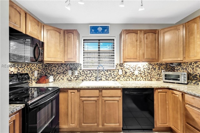 kitchen featuring light stone counters, backsplash, sink, and black appliances