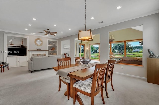 dining area featuring crown molding, built in shelves, a fireplace, and light colored carpet