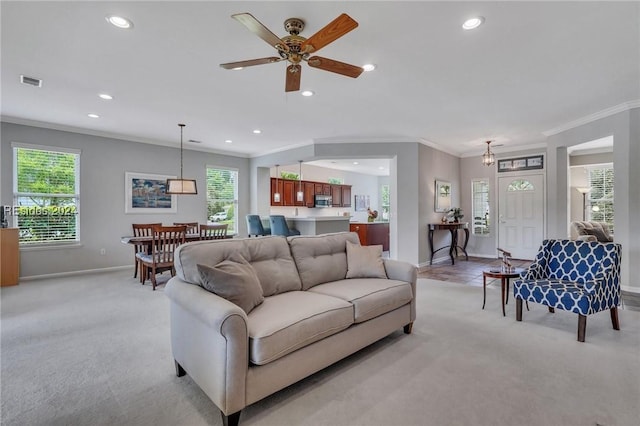 living room with crown molding, light colored carpet, and a healthy amount of sunlight