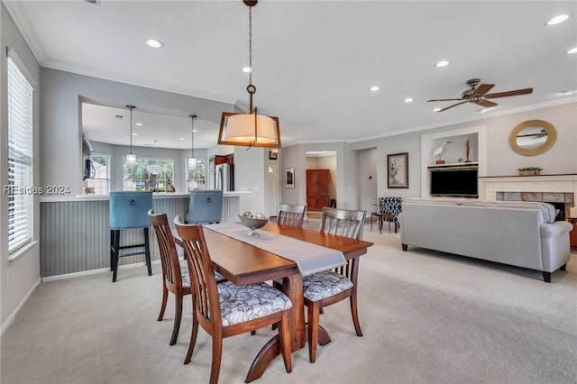 carpeted dining space with ornamental molding, plenty of natural light, and a fireplace