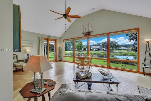 living room with a healthy amount of sunlight, light wood-type flooring, ceiling fan, and a water view