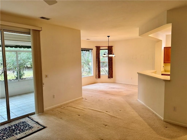 carpeted empty room with an inviting chandelier