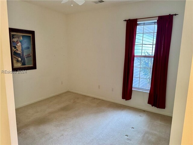 spare room with ceiling fan and light carpet