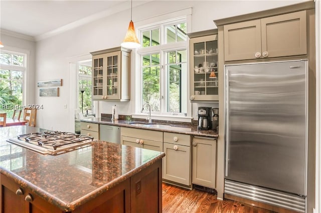 kitchen with sink, crown molding, dark stone counters, pendant lighting, and stainless steel appliances