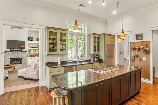 kitchen featuring appliances with stainless steel finishes, sink, dark stone counters, hanging light fixtures, and green cabinetry