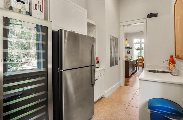 kitchen featuring sink, light tile patterned floors, stainless steel fridge, and white cabinets