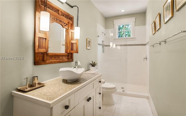 bathroom featuring tile patterned floors, toilet, vanity, and a tile shower