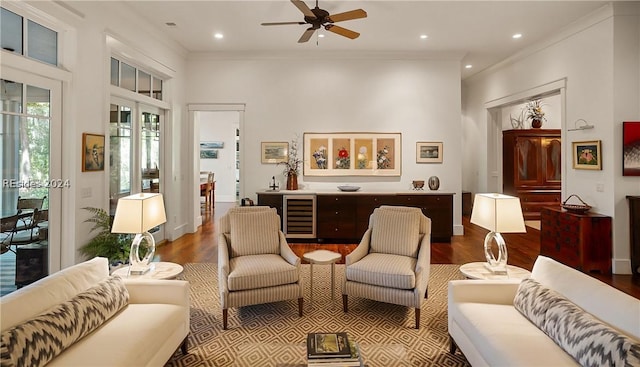 living room featuring hardwood / wood-style floors, ornamental molding, beverage cooler, and ceiling fan