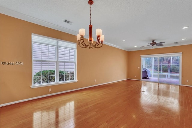 empty room featuring crown molding, ceiling fan with notable chandelier, hardwood / wood-style floors, and a textured ceiling