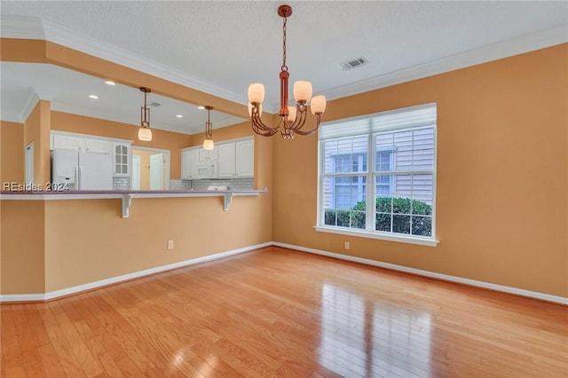 kitchen featuring white cabinets, a kitchen bar, kitchen peninsula, crown molding, and white appliances