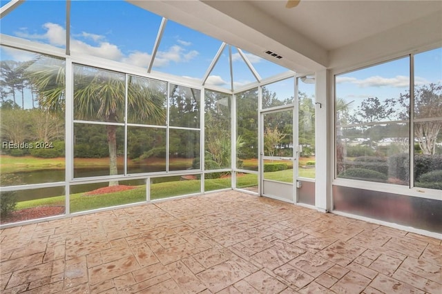 unfurnished sunroom with a water view and ceiling fan