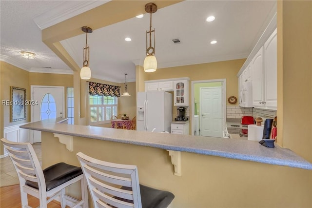 kitchen with a kitchen breakfast bar, white fridge with ice dispenser, and white cabinets