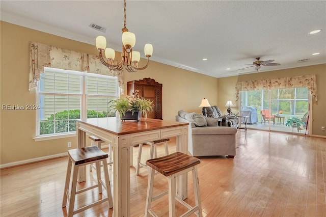 dining area featuring crown molding, ceiling fan with notable chandelier, and light hardwood / wood-style floors