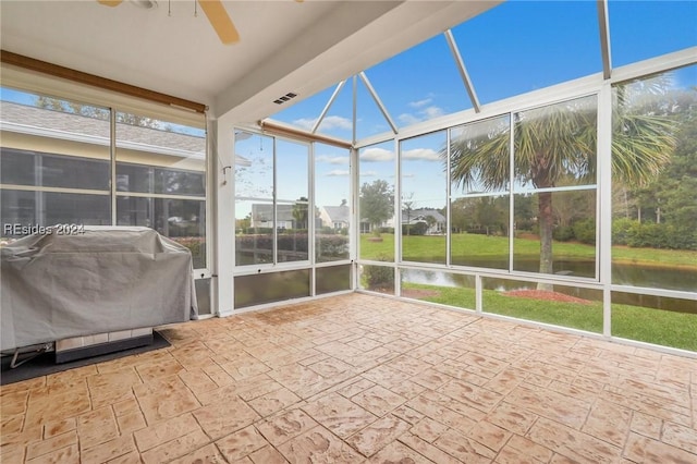 unfurnished sunroom featuring ceiling fan and a water view