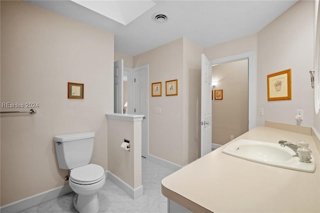 bathroom featuring vanity, toilet, and a skylight