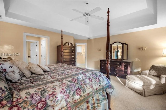 bedroom with ceiling fan, a tray ceiling, and carpet floors