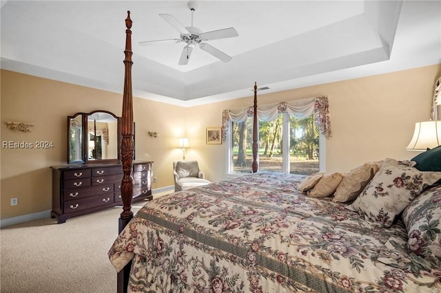 carpeted bedroom featuring access to exterior, a tray ceiling, and ceiling fan