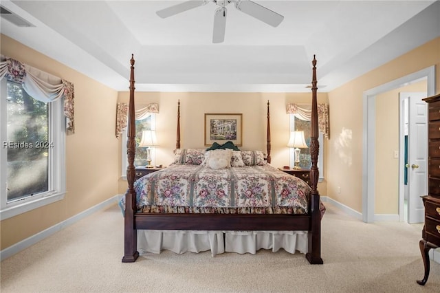 carpeted bedroom with ceiling fan and a raised ceiling