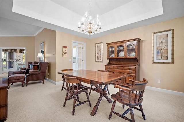 carpeted dining area featuring a raised ceiling, ornamental molding, and an inviting chandelier