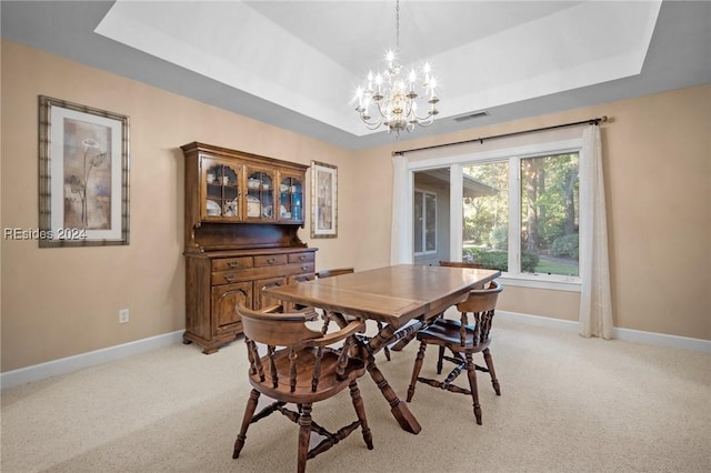 dining space with light colored carpet, a raised ceiling, and a chandelier